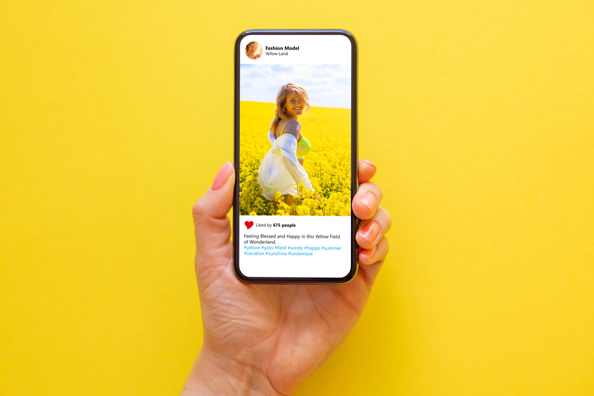 Mobile Phone on Yellow Background with Photo of Woman in Yellow Meadow on the Screen